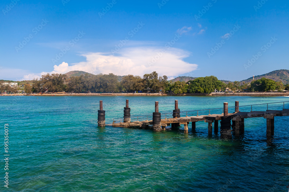 a picturesque pier at the rafai beach pier going under water with steps. Clear turquoise water and blue sky. Travel and recreation.