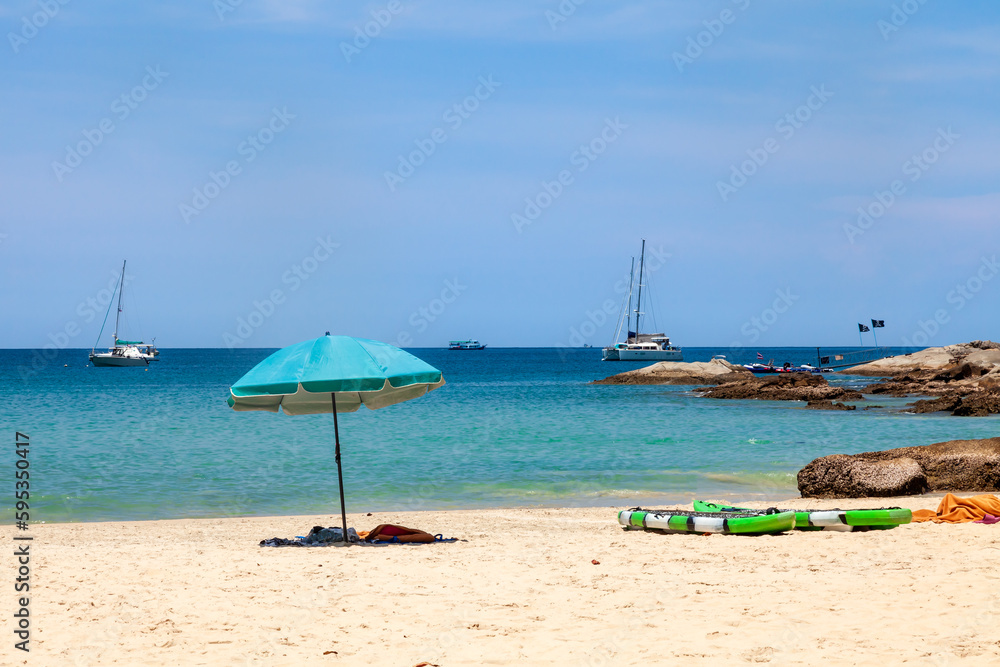 Fototapeta premium beautiful bright nai harn beach in thailand on phuket island with clear turquoise water in the sea, white sand with umbrella and blue sky. A popular tourist place in the hot countries of Asia.