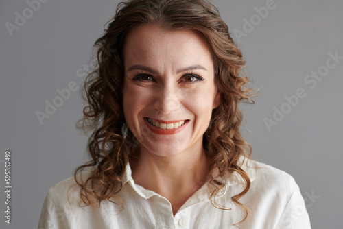 Face of happy mature woman with curly hair looking at camera