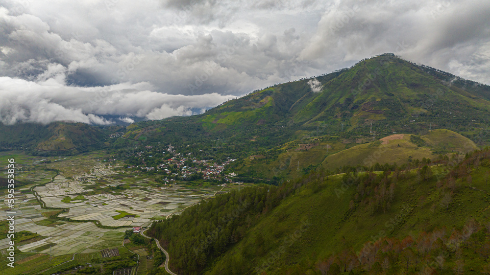 Fototapeta premium Aerial drone of farmland and town in the valley among the mountains. Sumatra, Indonesia.