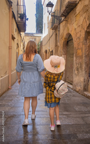 A woman and a girl are walking down the street of the old town. Vertical photo. Tarragona.