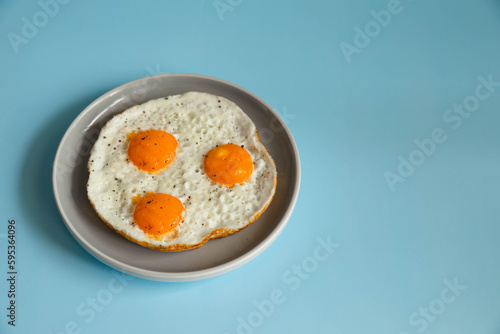Fried eggs in a plate on a blue background