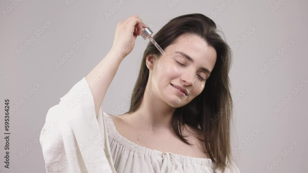 beautiful girl with a smiling face and holding a pipette with serum in front of her face, beauty with makeup and a perfect smile beautiful girl with a smiling face and holding a pipette with serum in front of her face, beauty with makeup and a perfect smile