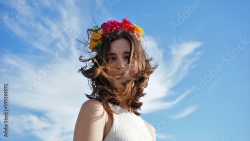 young woman with wreath against the sky