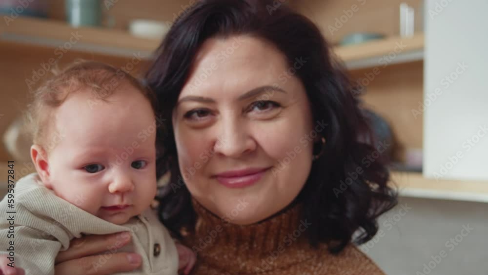 Close-up view of grandma holding newborn grandchild, smiling and laughing. Caucasian senior woman with her infant granddaughter. Family visit, multi-generational connections, happy memories Close-up view of grandma holding newborn grandchild, smiling and laughing. Caucasian senior woman with her infant granddaughter. Family visit, multi-generational connections, happy memories