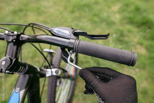 Mechanics Hand Repairing Bicycle in Bike Workshop. Closeup of Male Muscular Hand Examining and Fixing Modern Cycle Transmission System. Bike Maintenance and Sport Shop Concept