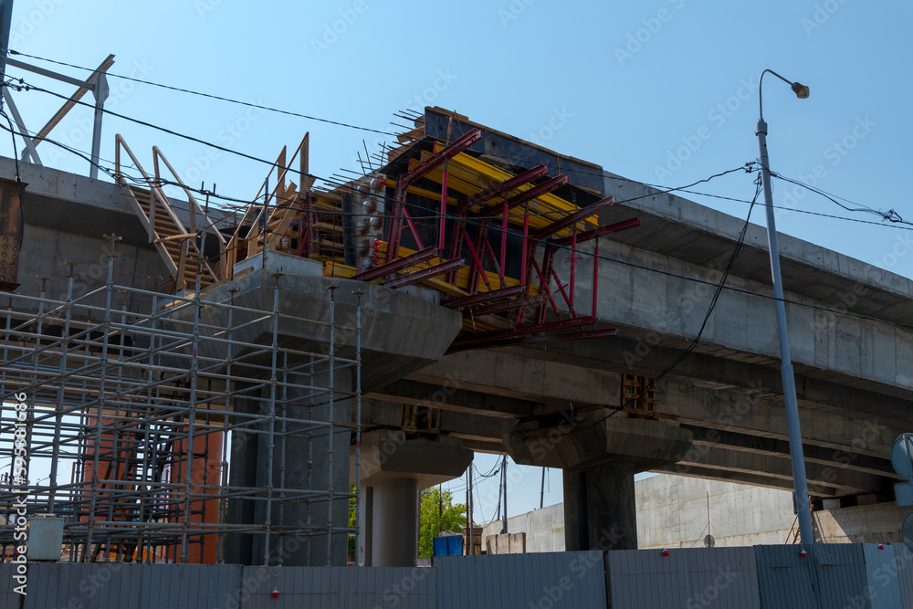 Naklejka premium Subway bridge under construction in summer city against blue sky. Modern transportation theme.