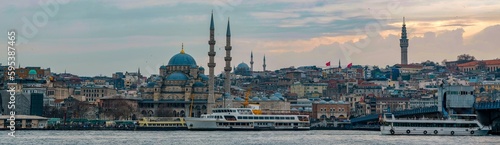 New Mosque Ottoman imperial mosque located in the Eminönü quarter of Istanbul, Turkey. Strait of Bosporus with ships in foreground and sunset in background. Turkey 2023 photo