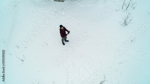 An aerial shot looking down at a man flying his drone in the snow