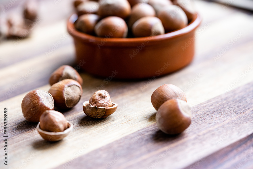 Hazelnuts in a shell and nutshells in ceramic bowl on rustic cutting board Hazelnuts in a shell and nutshells in ceramic bowl on rustic cutting board