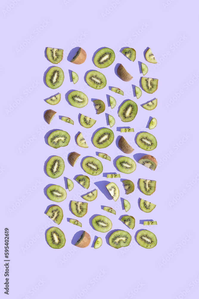 Kiwi fruit arranged in a rectangle on a purple background. Copy space for text. Summer aesthetic visual concept.