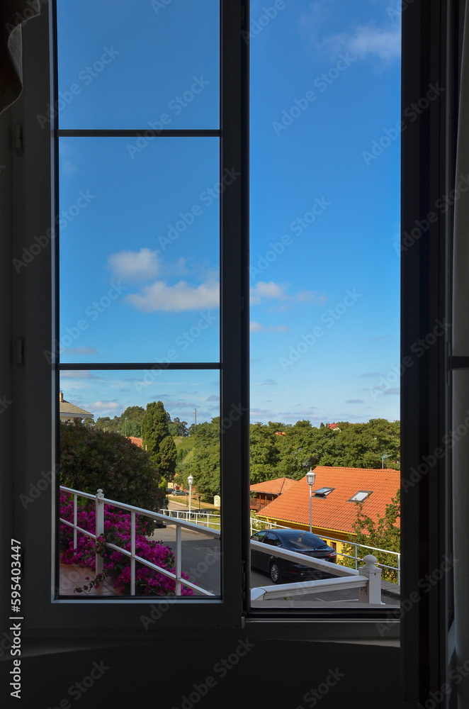 Magnificent view from a room with a large open window, towards the town of Perlora and its trees and green vegetation, on a sunny day. Magnificent view from a room with a large open window, towards the town of Perlora and its trees and green vegetation, on a sunny day.