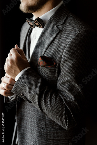 a young and handsome groom in a suit and a vest with a bow tie is assembled for the wedding. successful entrepreneur marries. successful man. portrait of the groom