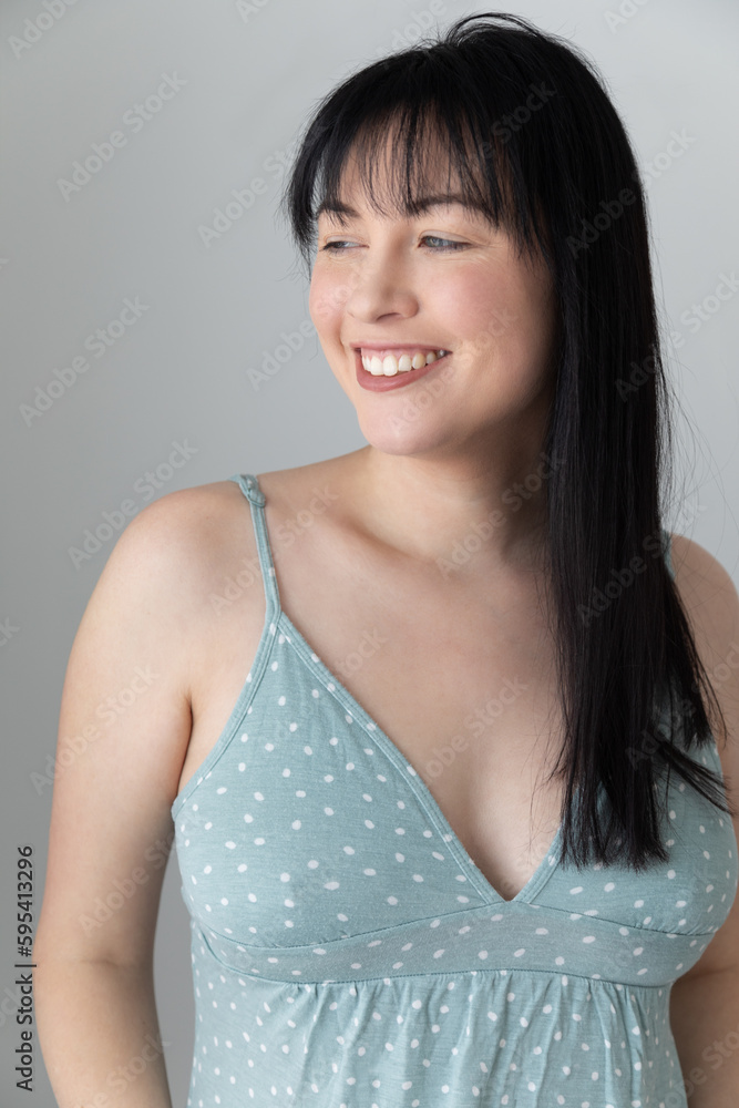 Close up portrait of a caucasian woman wearing a blue polka dot pajama top. She is smiling and has black hair and blue eyes. She is in her 30s. Close up portrait of a caucasian woman wearing a blue polka dot pajama top. She is smiling and has black hair and blue eyes. She is in her 30s.
