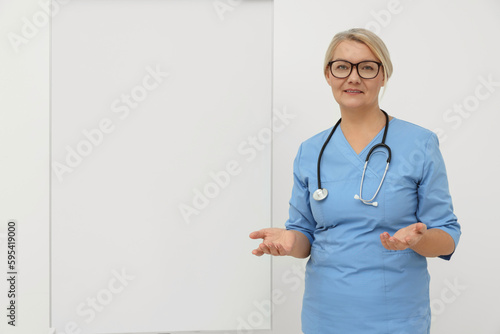 Professional doctor explaining something near flipchart, space for text