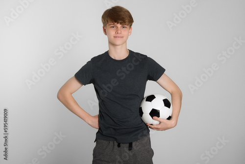 Teenage boy with soccer ball on light grey background
