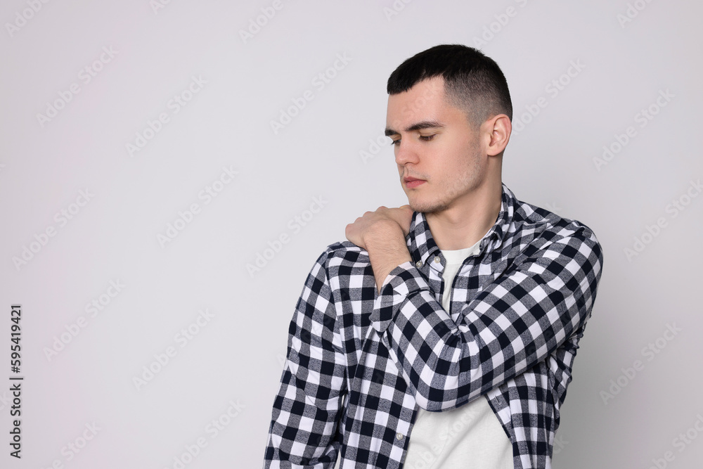 Fototapeta premium Man suffering from pain in his shoulder on light background, space for text. Arthritis symptoms