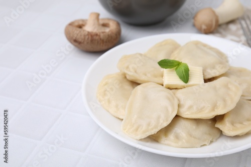 Delicious dumplings (varenyky) with tasty filling and butter on white table, closeup. Space for text