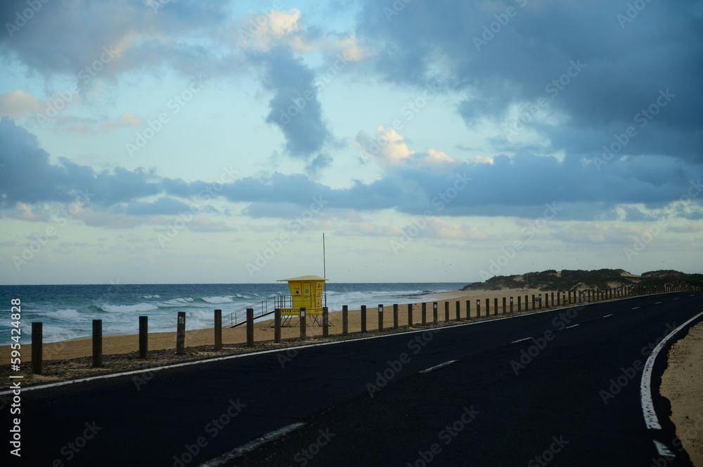 Driving car on black asphalt road through white sandy dunes near Corallejo beach on sunset Fuerteventura, Canary islands, Spain