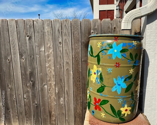 Painted Flowers on Green Rain Barrel by Wood Fence photo