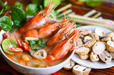 Shrimp soup on seafood soup bowl with thai herb and spices, Thai Food Tom Yum Kung, Hot and sour spicy shrimps prawns soup  curry lemon lime galangal red chili straw mushroom on table food