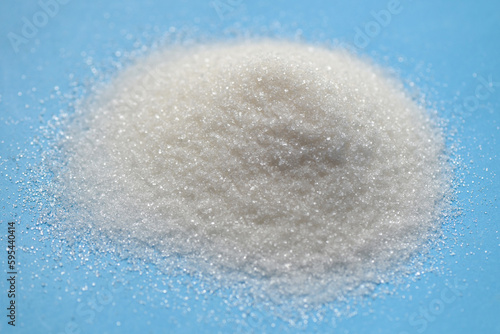 heap of sugar on blue background, white sugar for food and sweets dessert candy heap of sweet sugar crystalline granulated