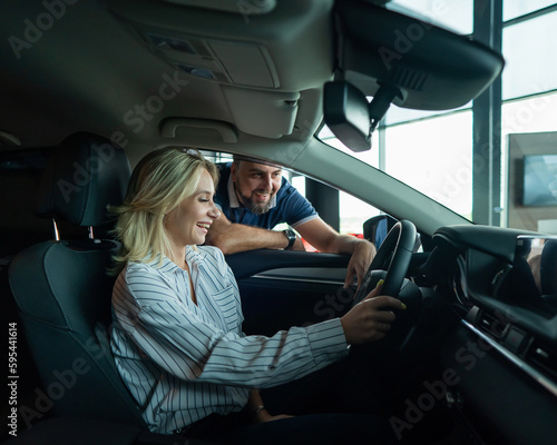 Caucasian family chooses a car. A woman is driving and a man is looking out the window. © Михаил Решетников