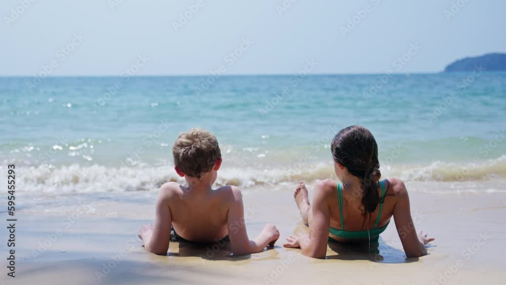 Back View Of Kids Relaxing On The Beach Back View Of Kids Relaxing On The Beach