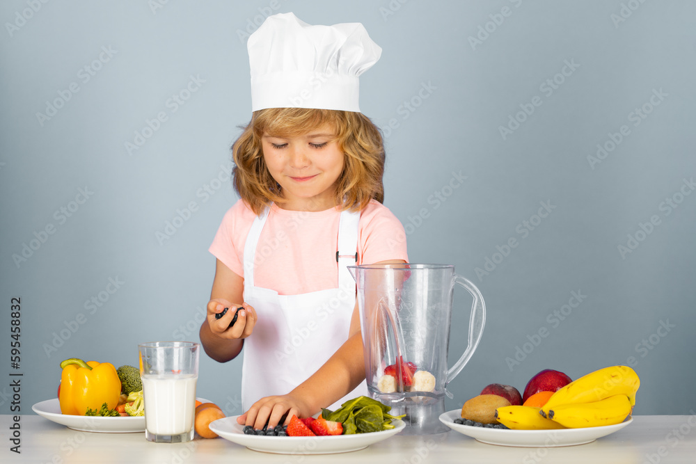 Child chef dressed cook baker apron and chef hat make smoothie isolated on studio background. Healthy nutrition kids food. Child chef dressed cook baker apron and chef hat make smoothie isolated on studio background. Healthy nutrition kids food.