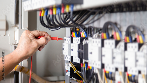 Electrical engineer checking the operation of electrical control cabinet, maintenance concept.  © bancha