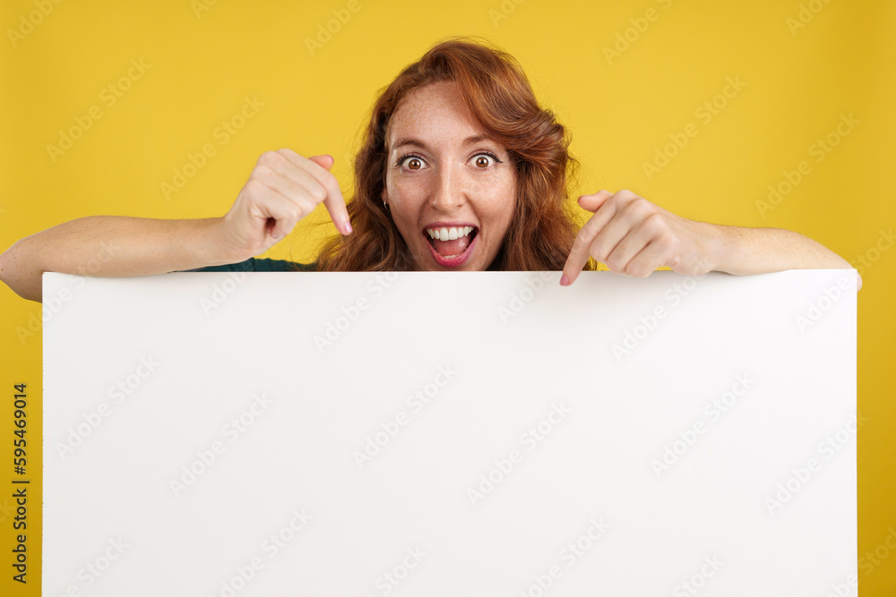 Amazed redheaded woman pointing to a panel with blank space Amazed redheaded woman pointing to a panel with blank space