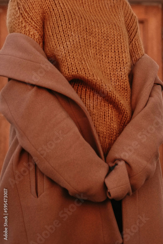 Details of orange warm cozy female sweater and brown coat. Outdoor portrait. Autumn winter street style cloth collection