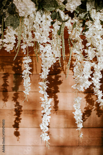 White fabric wedding florals against a rustic wood wall