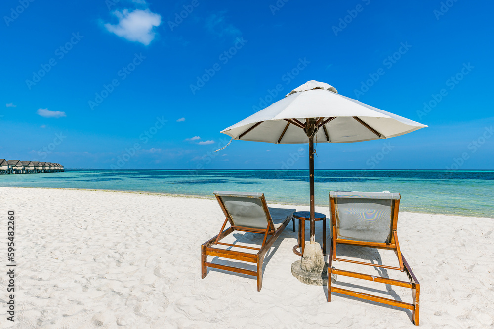 Seascape with two chaise longues, without people. Beautiful beach ocean vacation destination scene. Amazing Maldives island. Beach scene with copy space for text. Luxury summer holiday concept
