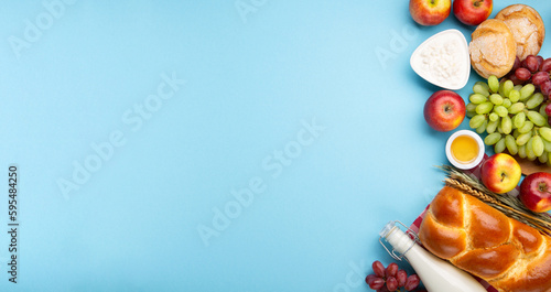 Jewish Shavuot Holiday Card. Dairy Products, Apples, Cheese, Grapes, Bread, Milk on Blue Background.