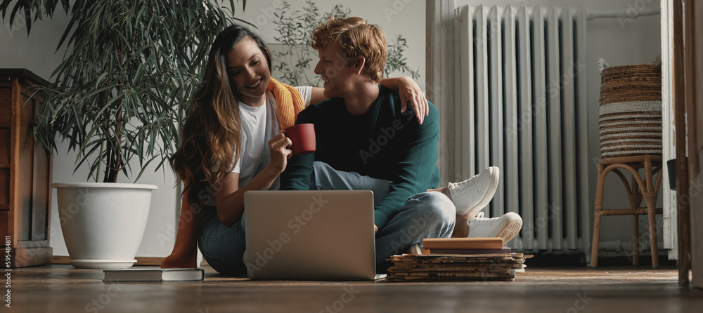 Relaxed young couple using laptop while sitting on the floor at home together Relaxed young couple using laptop while sitting on the floor at home together