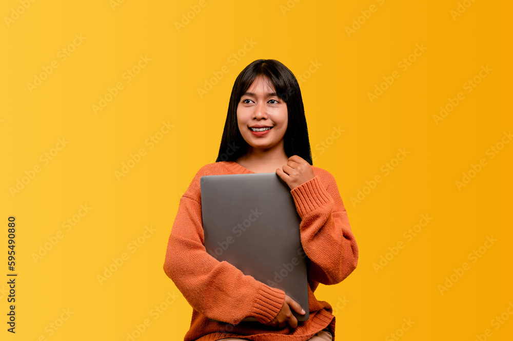 Asian woman and laptop and are happy to work Photo of a beautiful Asian woman who is happy working at home. using a laptop computer yellow studio work at home concept Asian woman and laptop and are happy to work Photo of a beautiful Asian woman who is happy working at home. using a laptop computer yellow studio work at home concept