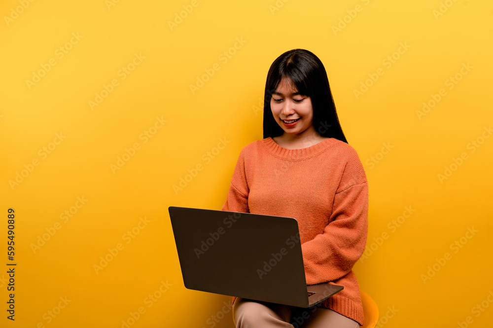 Asian woman and laptop and are happy to work Photo of a beautiful Asian woman who is happy working at home. using a laptop computer yellow studio work at home concept Asian woman and laptop and are happy to work Photo of a beautiful Asian woman who is happy working at home. using a laptop computer yellow studio work at home concept