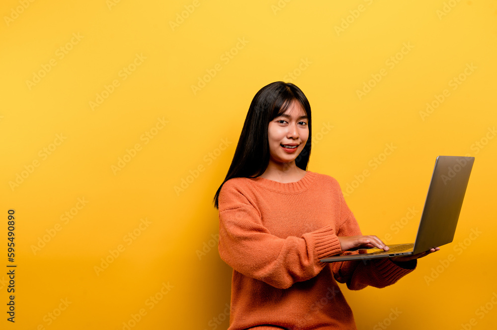 Asian woman and laptop and are happy to work Photo of a beautiful Asian woman who is happy working at home. using a laptop computer yellow studio work at home concept Asian woman and laptop and are happy to work Photo of a beautiful Asian woman who is happy working at home. using a laptop computer yellow studio work at home concept