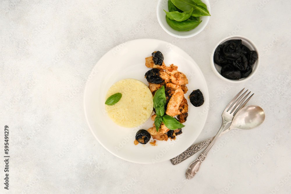 Couscous with chicken meat and prunes with walnuts on a gray background.