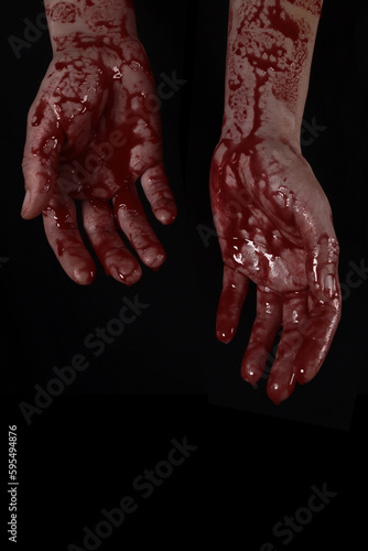 Raised bloody creepy hands on a black background, the concept of murder, nightmares, Halloween. Vertical Orientation © Michael