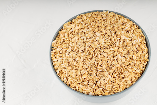 Oat flakes bowl on a white background. Raw oatmeal for a healthy breakfast. Copy space. Top view