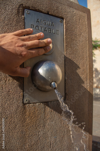 Man drinking water from a public fountain in a summer with heat and months of drought.