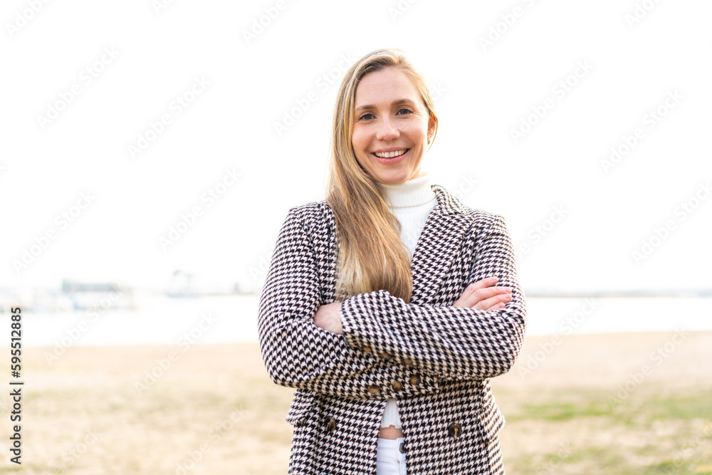 Young blonde woman at outdoors keeping the arms crossed in frontal position
