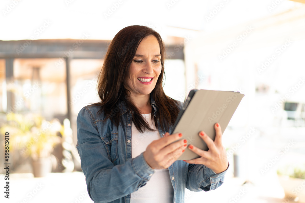Middle aged woman holding a tablet with happy expression Middle aged woman holding a tablet with happy expression