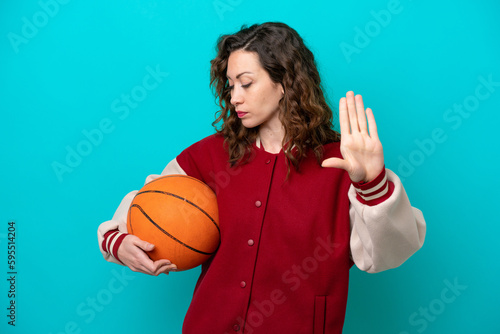 Young caucasian basketball player woman isolated on blue background making stop gesture and disappointed © luismolinero