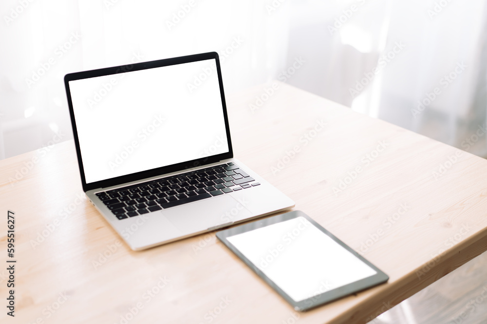 Fototapeta premium Laptop and tablet with blank screens for text or advertising on wooden table.