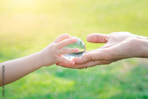 Tablou canvas Adult person passes crystal ball to baby hand a healthy ecology to a new generation