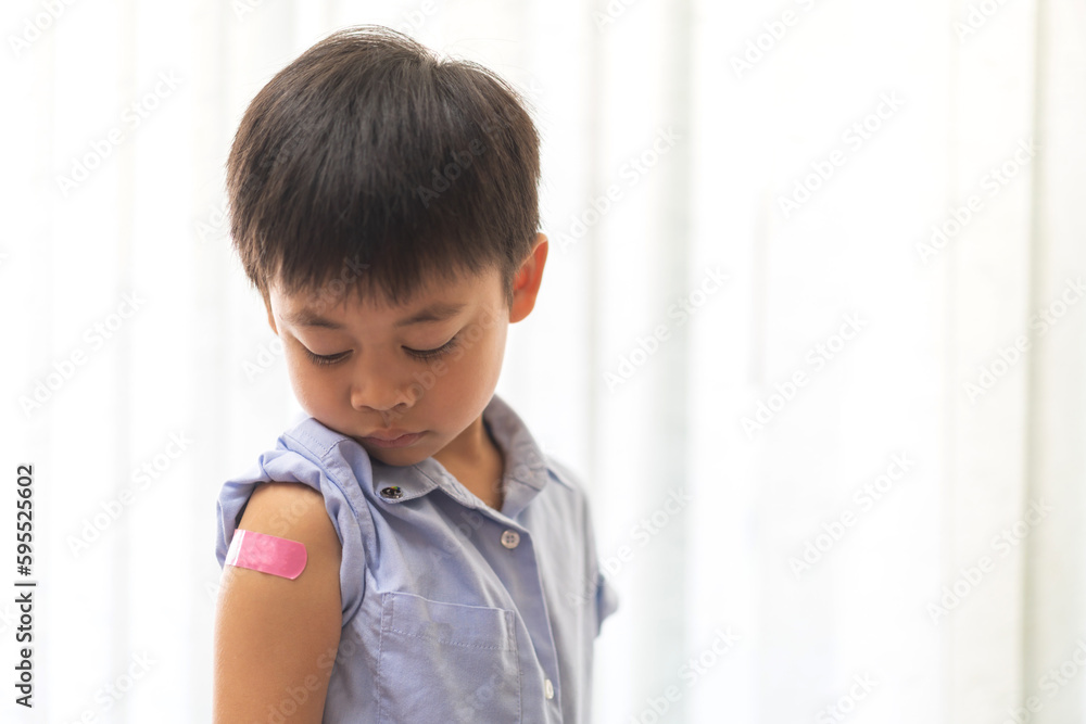 Portrait of happy smile vaccinated little asian kid boy children ages 5 to 11 years old posing show arm with medical plaster after Injection vaccine Covid-19 protection.coronavirus vaccination kid Portrait of happy smile vaccinated little asian kid boy children ages 5 to 11 years old posing show arm with medical plaster after Injection vaccine Covid-19 protection.coronavirus vaccination kid