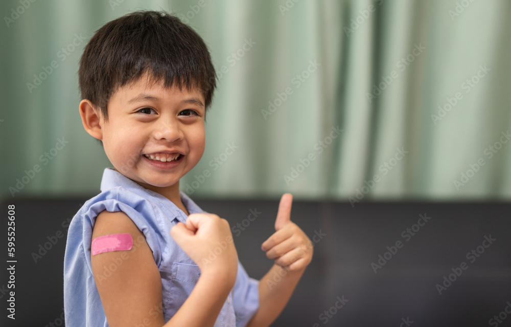 Portrait of happy smile vaccinated little asian kid boy children ages 5 to 11 years old posing show arm with medical plaster after Injection vaccine Covid-19 protection.coronavirus vaccination kid Portrait of happy smile vaccinated little asian kid boy children ages 5 to 11 years old posing show arm with medical plaster after Injection vaccine Covid-19 protection.coronavirus vaccination kid